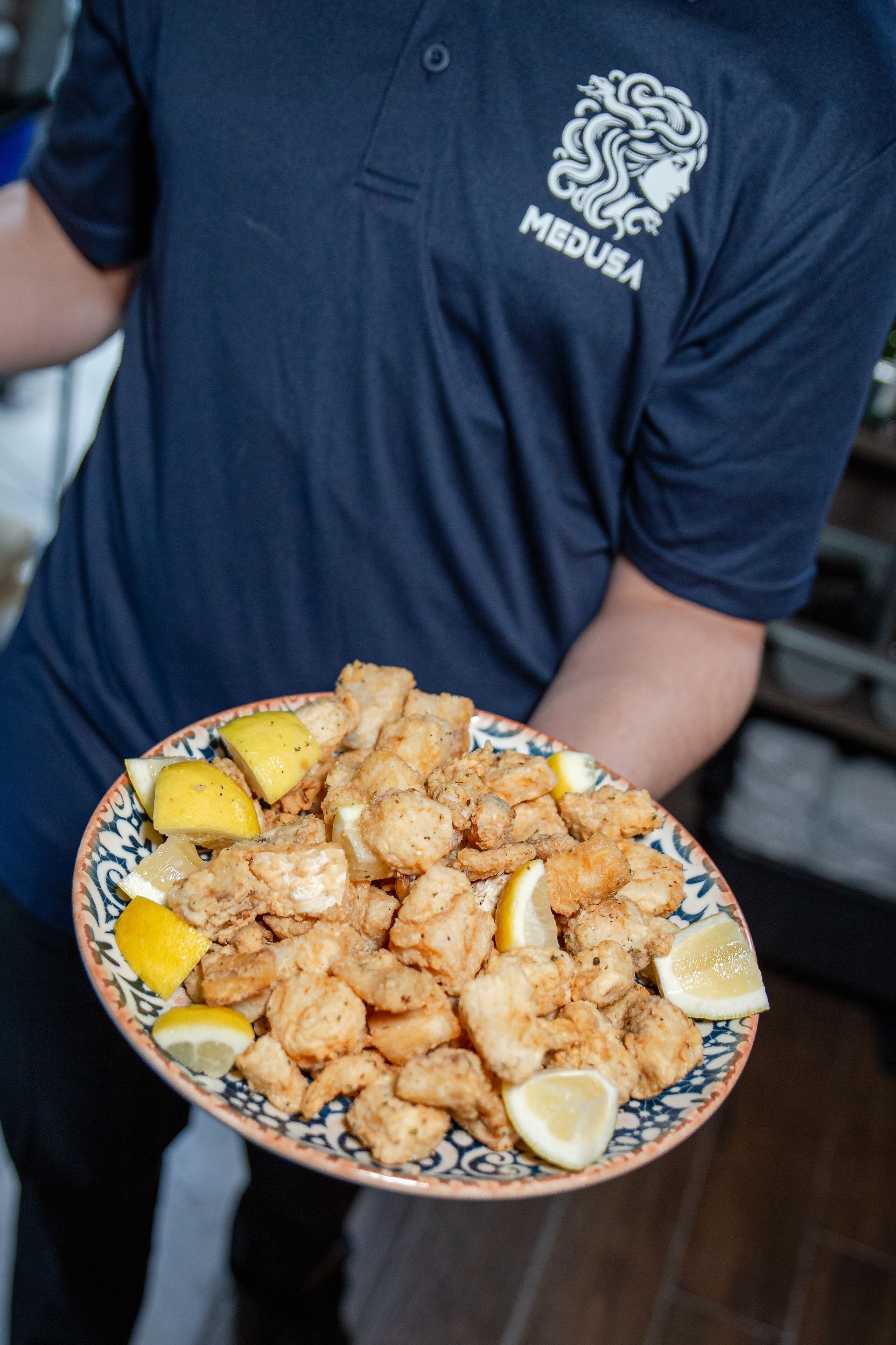 A man in a medusa shirt is holding a plate of food.