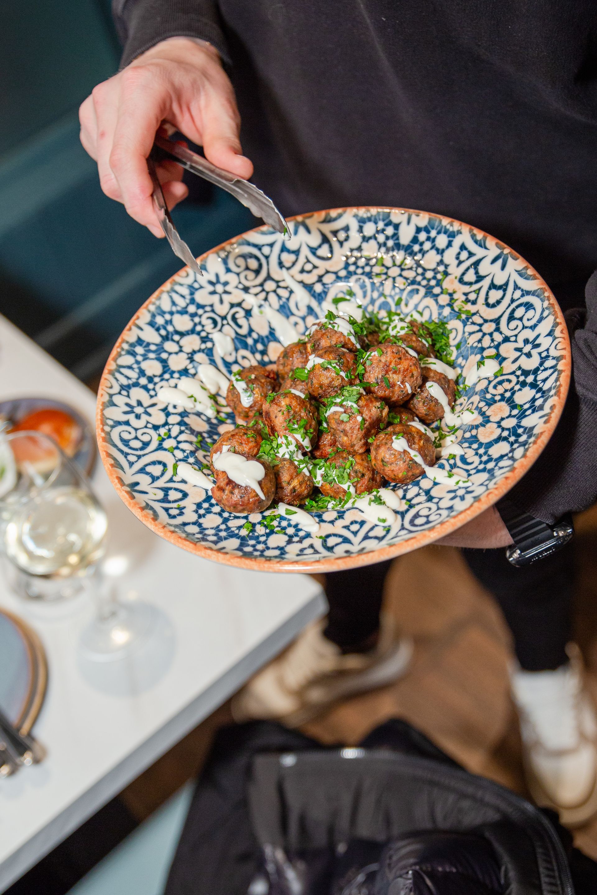 A person is holding a plate of food with meatballs on it.