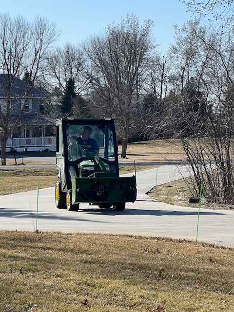 A man is driving a green tractor down a road.
