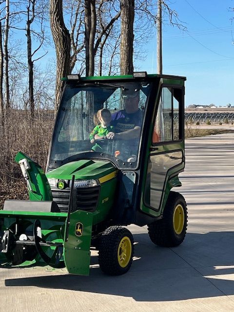 A man is driving a green john deere snow blower