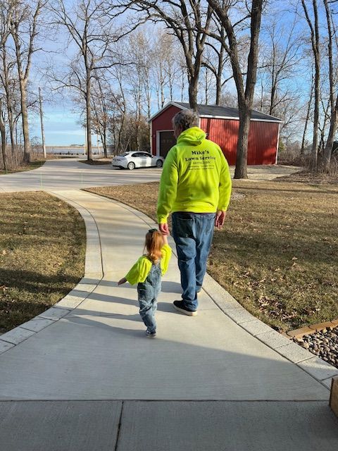 A man and a child are walking down a sidewalk holding hands.
