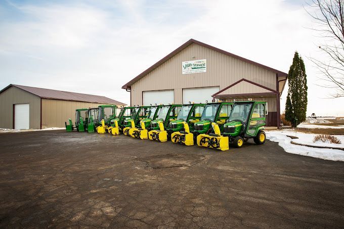 A row of john deere snow blowers are parked in front of a building.