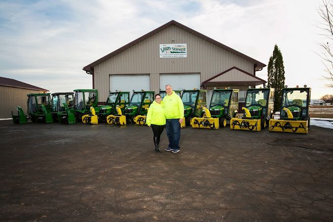 A man and a woman are standing in front of a row of tractors.