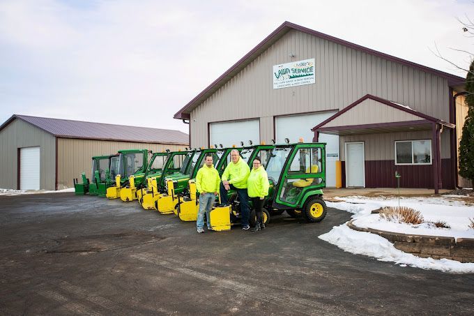 A group of people standing in front of a building next to a row of tractors.
