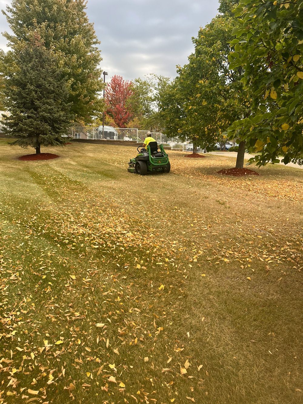 A person is riding a lawn mower in a park.