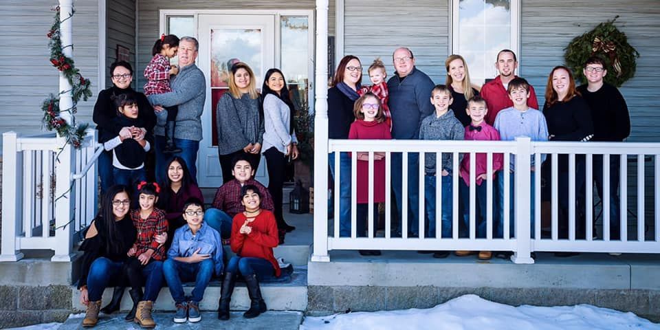 A large family is posing for a picture on the porch of their house.
