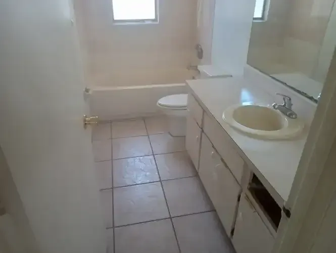 Bathroom with white fixtures, sink, toilet, tub, and tiled floor.