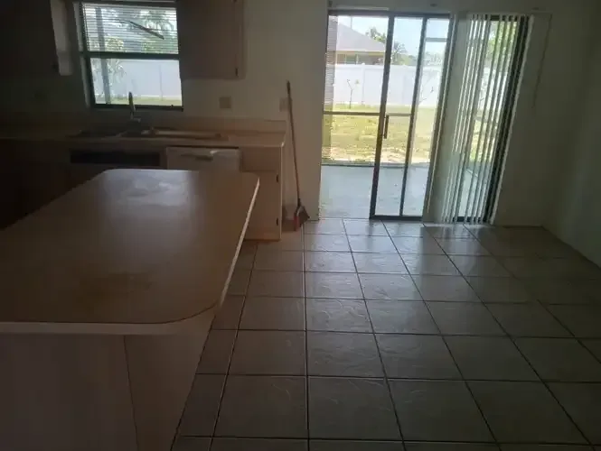 Kitchen with light tile floor, beige countertops, and sliding glass doors to a patio.