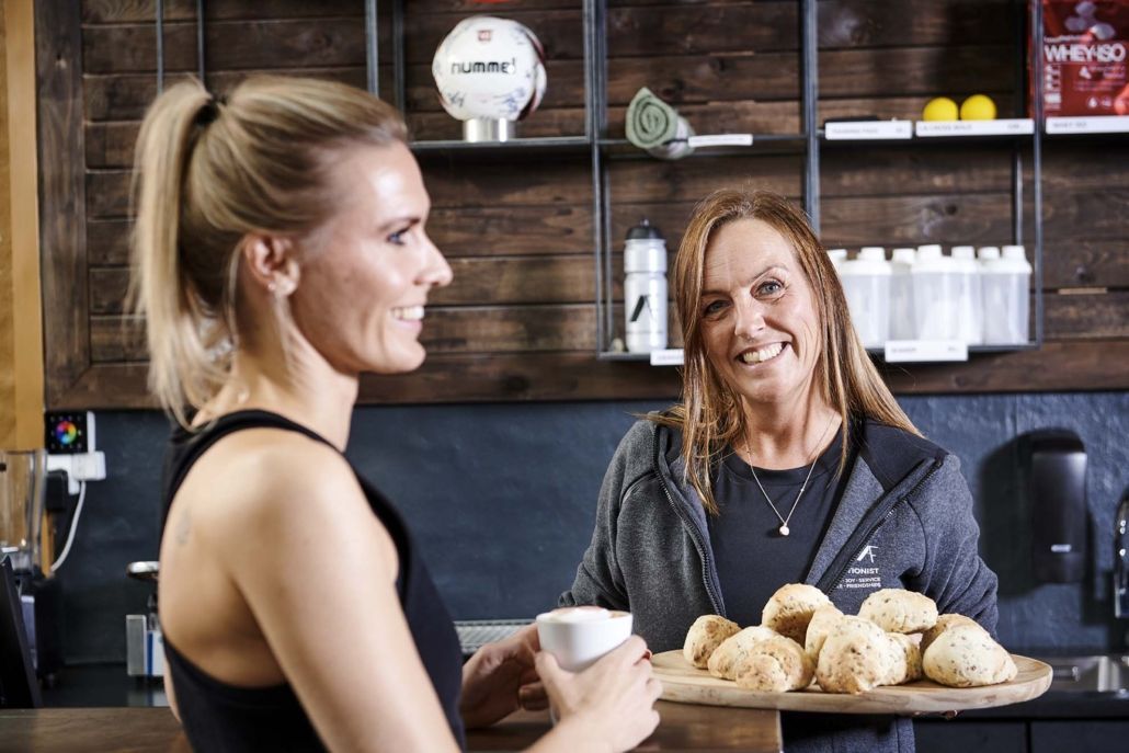 To kvinder står ved siden af ​​hinanden i et køkken.