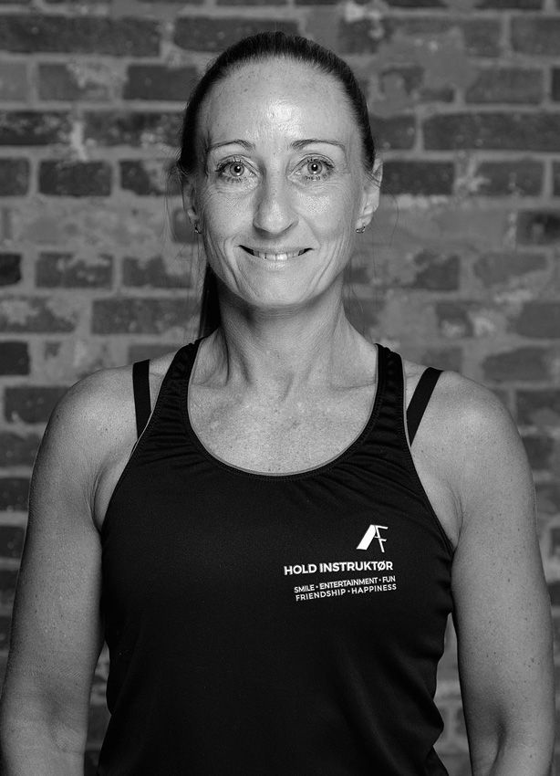 En kvinde i en orange tanktop smiler, mens hun holder et par håndvægte.