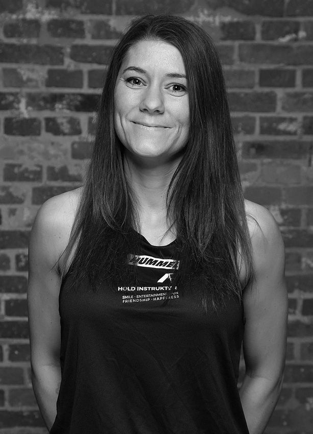 Et sort/hvidt foto af en kvinde, der står foran en murstensvæg.