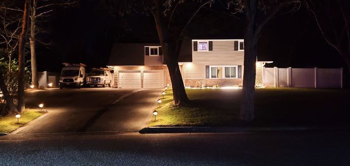 A house is lit up at night with a car parked in front of it