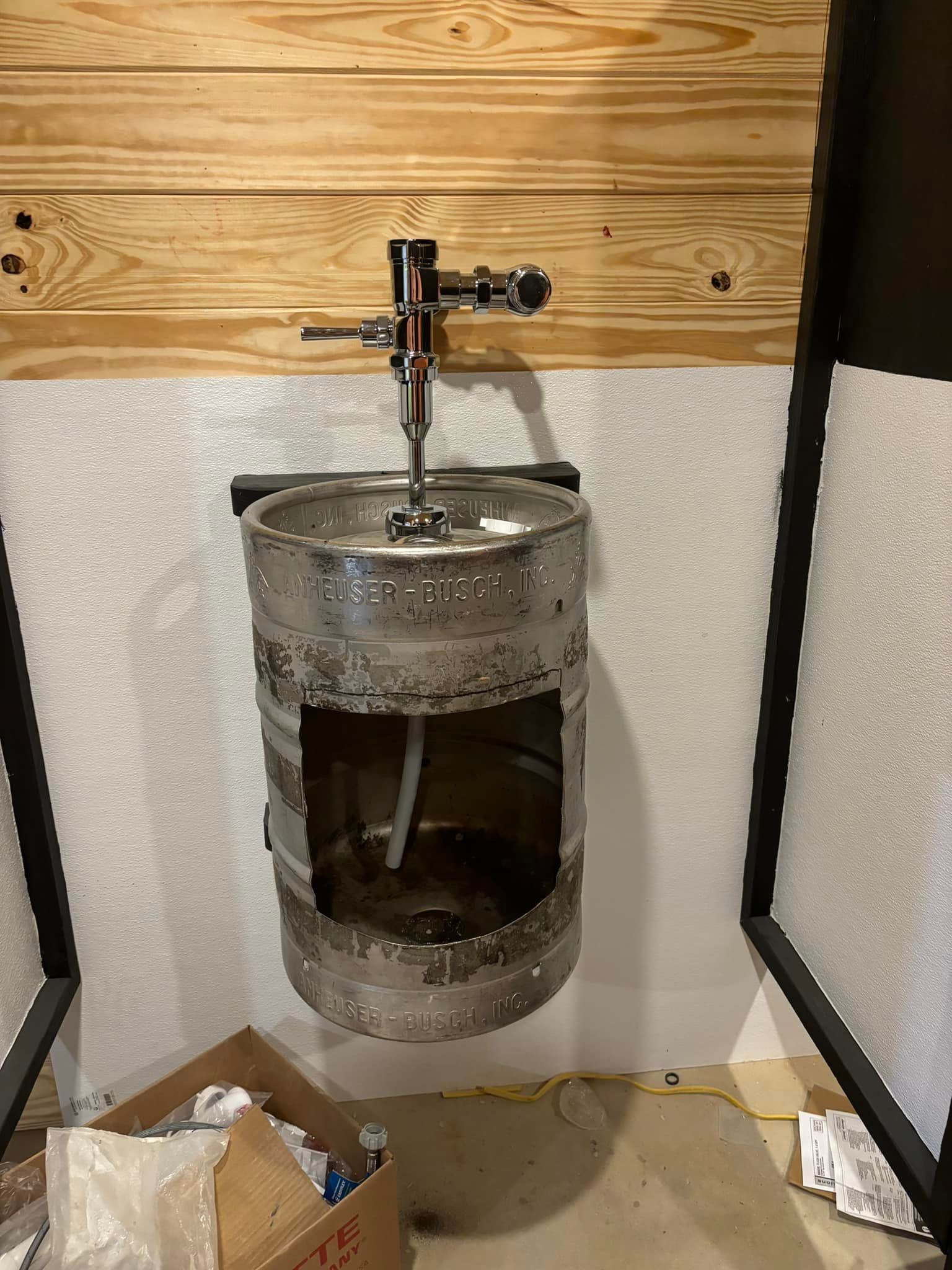 A urinal made out of a beer keg in a bathroom.