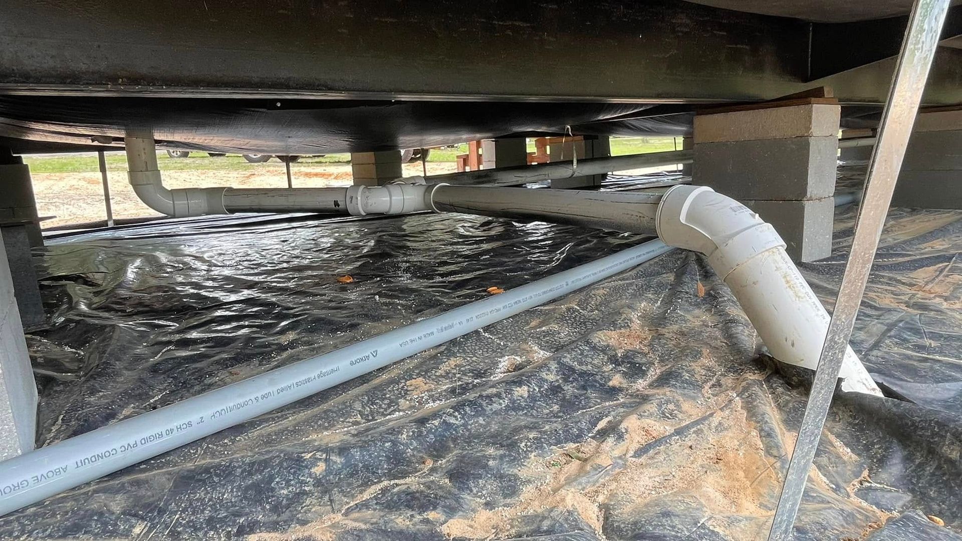 A hose is connected to a pipe under a vehicle.