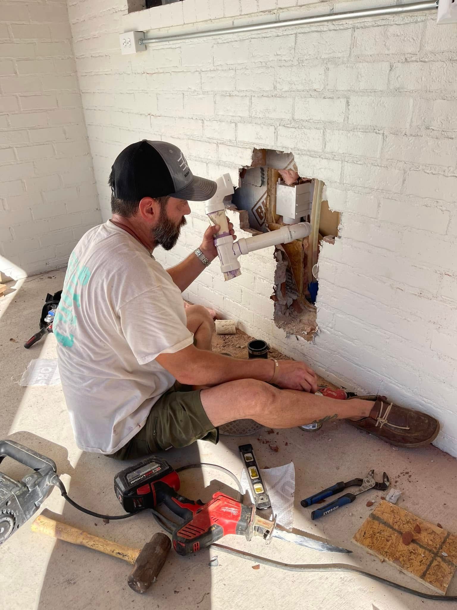 A man is sitting on the floor working on a pipe.