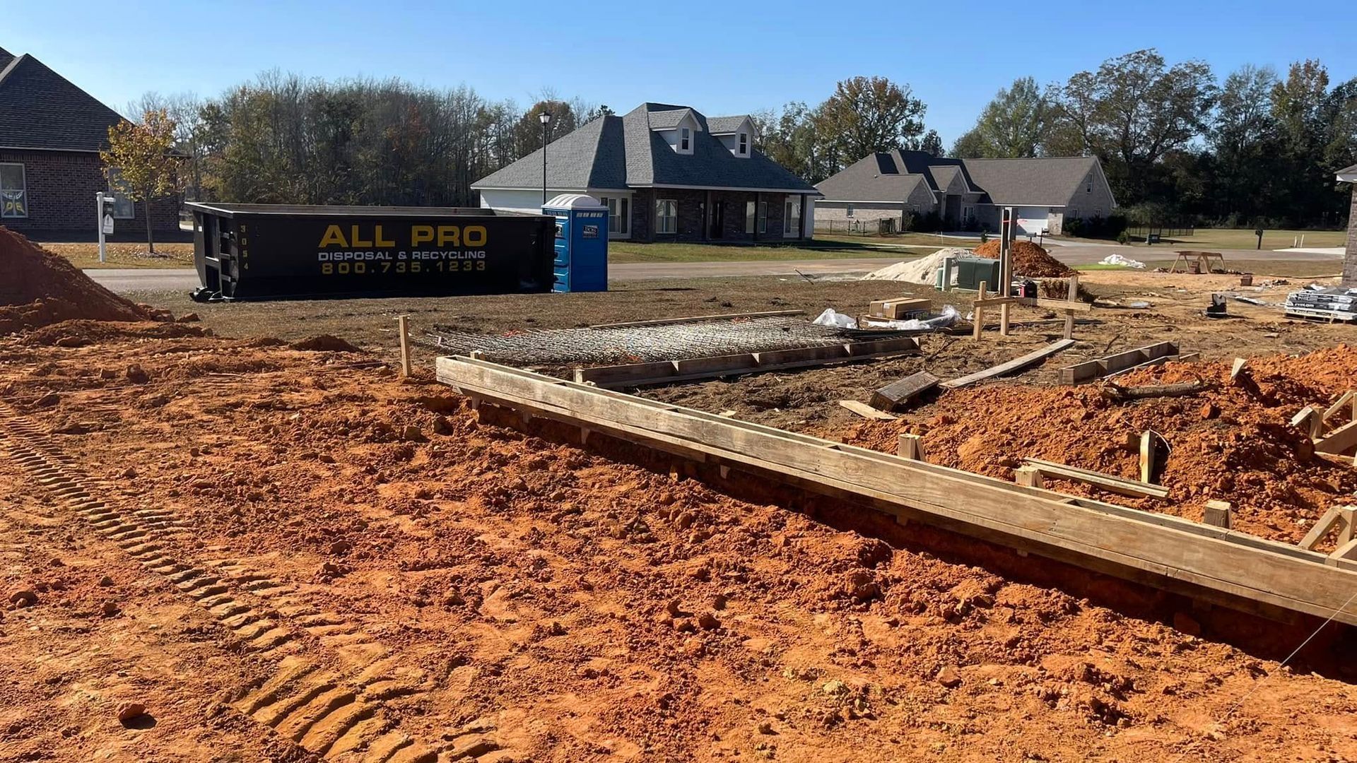 A construction site with a dumpster that says all pro on it