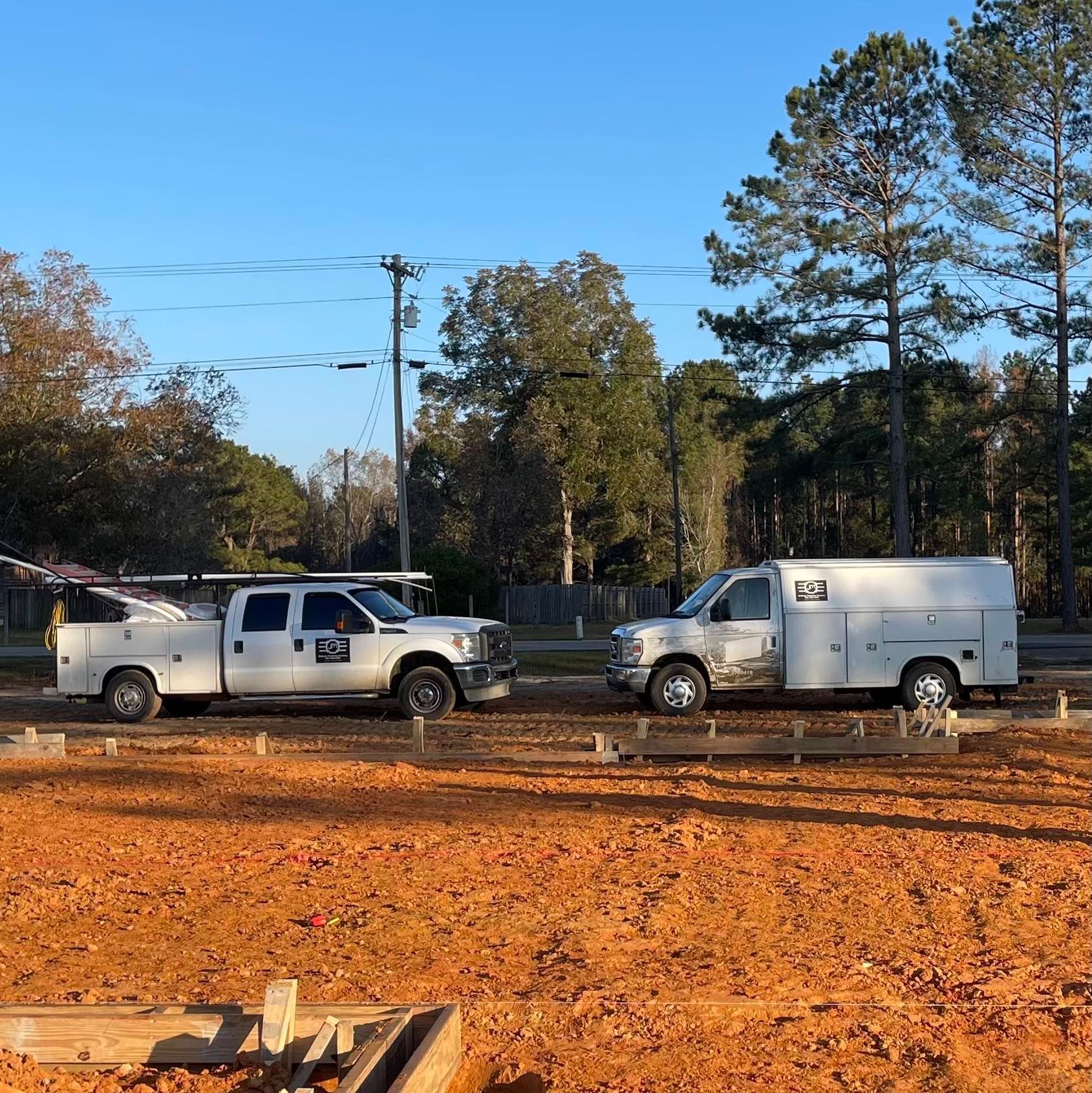Two trucks are parked next to each other in a dirt field