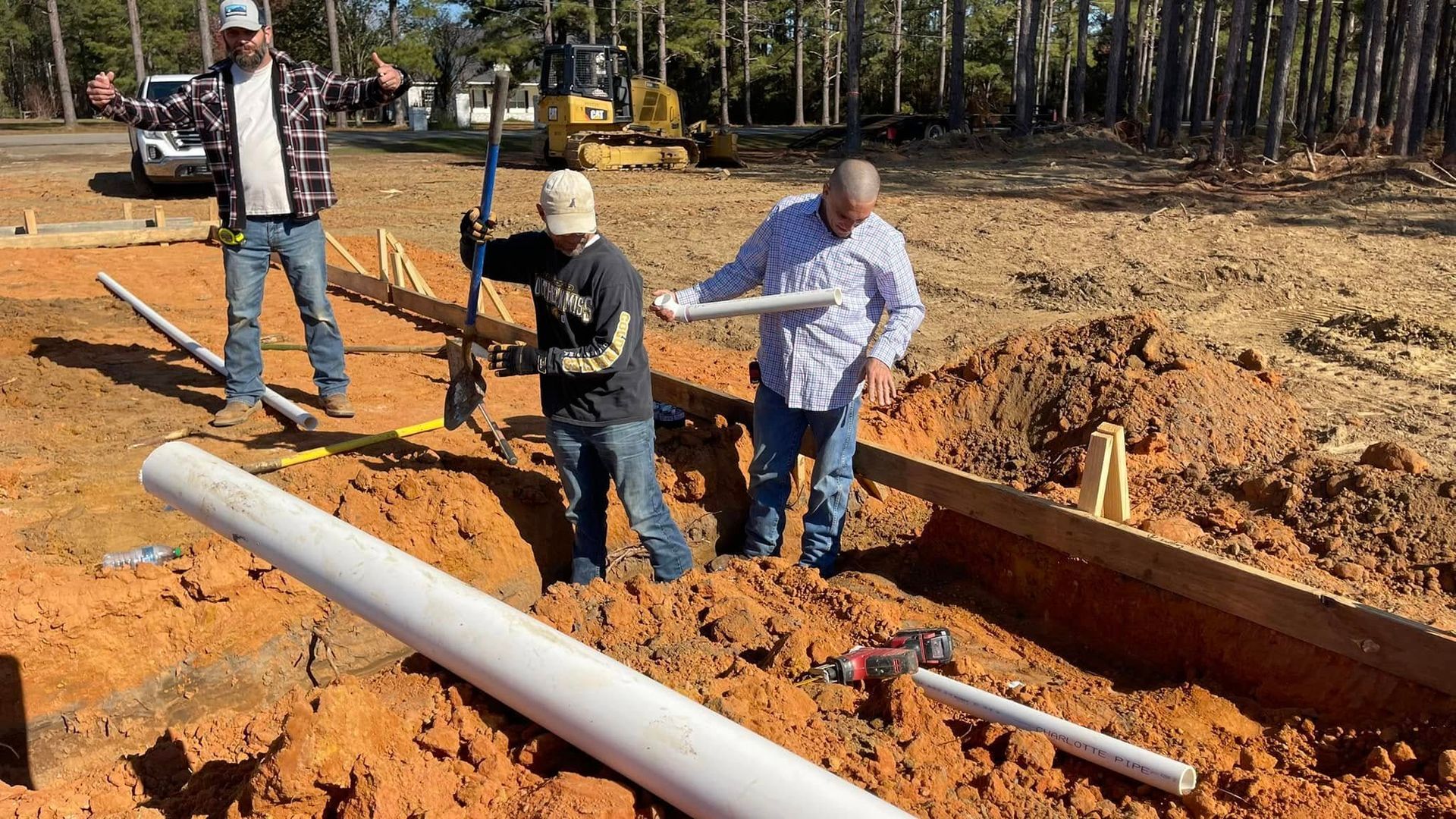 A group of construction workers are digging a hole in the dirt.