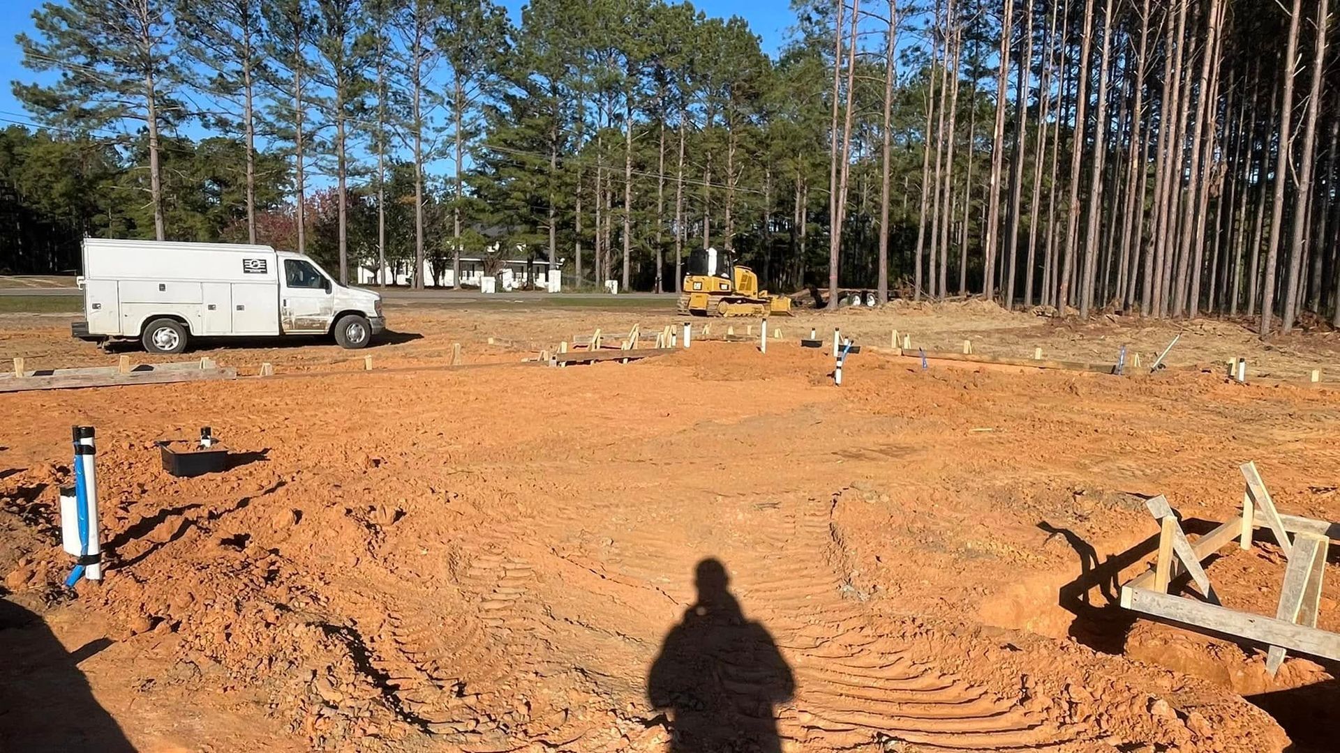 A white truck is parked in the middle of a dirt field.