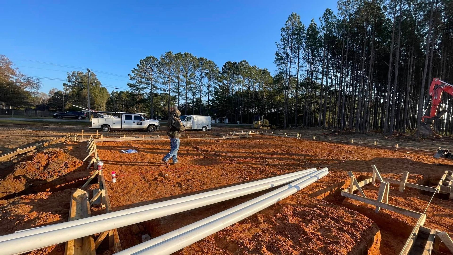 A construction site with a lot of pipes in the dirt.