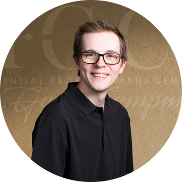 Man wearing glasses smiles, in a black shirt, set against a brown background with text.