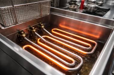 Electric commercial deep fryer with glowing, hot metal heating elements submerged in cooking oil.