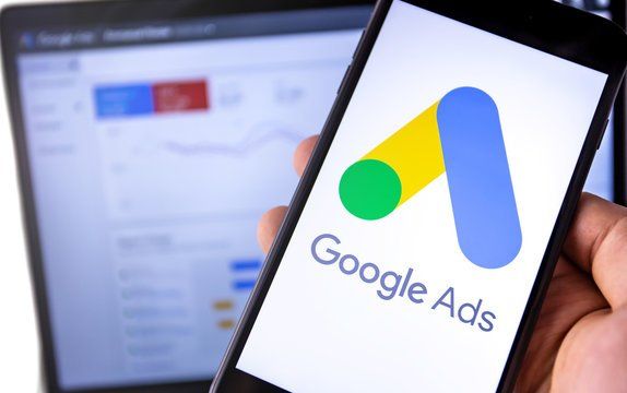 A person is holding a cell phone with the google ads logo on it.