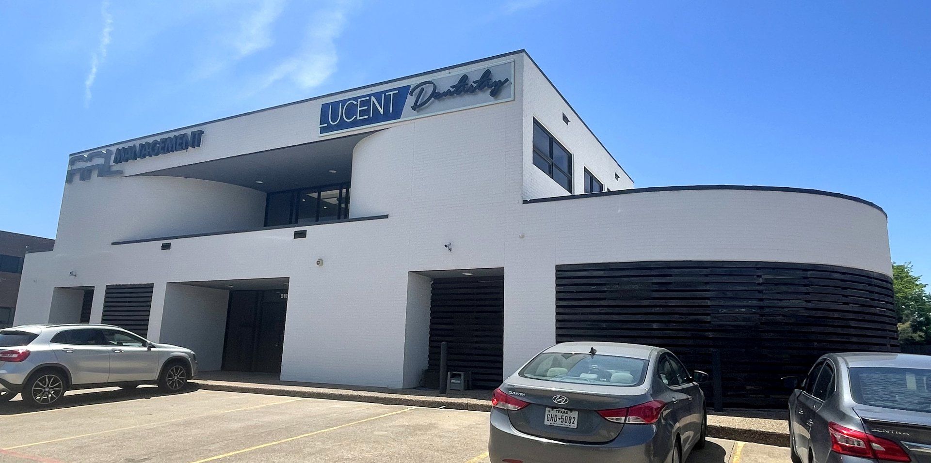 A white building with cars parked in front of it.