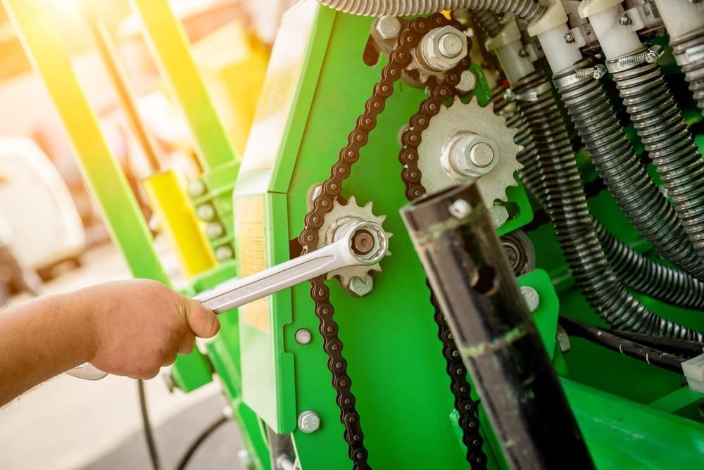 A Person Is Working on A Green Machine with A Wrench — Parkes Machinery Services PTY LTD in Parkes, NSW