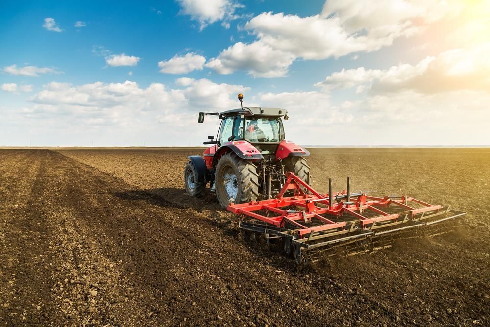 A Tractor Is Plowing a Field on A Sunny Day — Parkes Machinery Services PTY LTD in Parkes, NSW