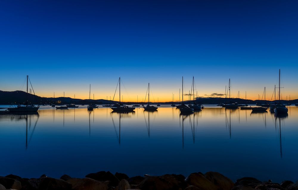 A Row of Boats Are Docked in A Harbor at Sunset — Parkes Machinery Services PTY LTD in West Wyalong, NSW