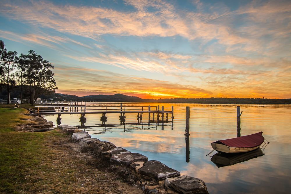 A Boat Is Docked at A Dock in The Water at Sunset — Parkes Machinery Services PTY LTD in Young, NSW
