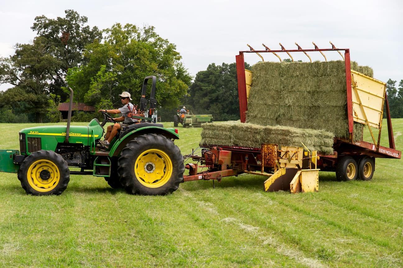 A John Deere Tractor Is Pulling a Trailer Full of Hay — Parkes Machinery Services PTY LTD in Condo, NSW