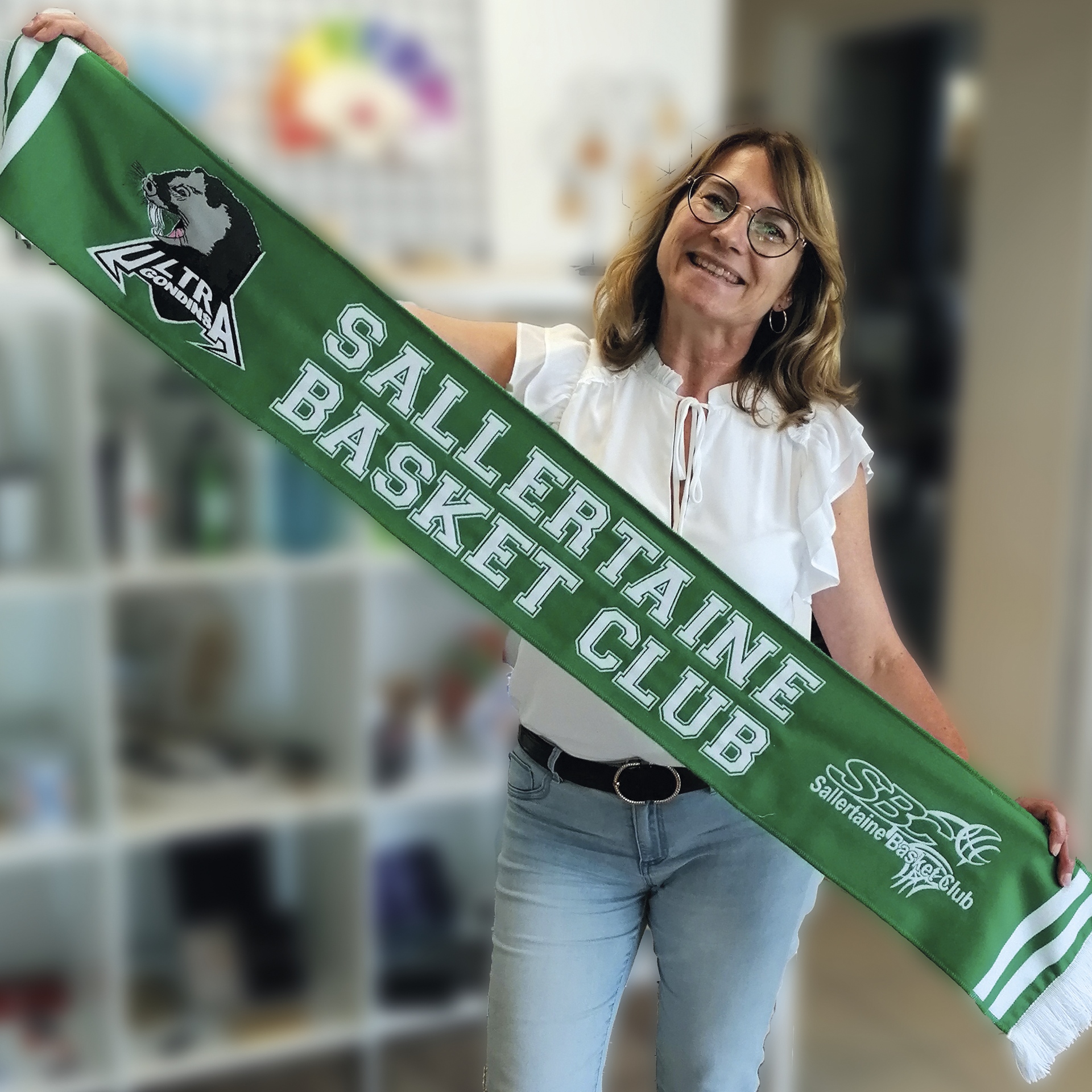 Femme en chemisier blanc et jean tenant une écharpe verte avec 