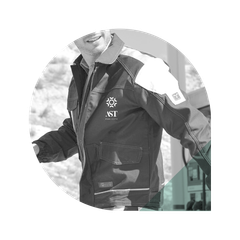 Homme portant une veste de travail avec logo et bandes réfléchissantes, souriant. Extérieur, en noir et blanc.