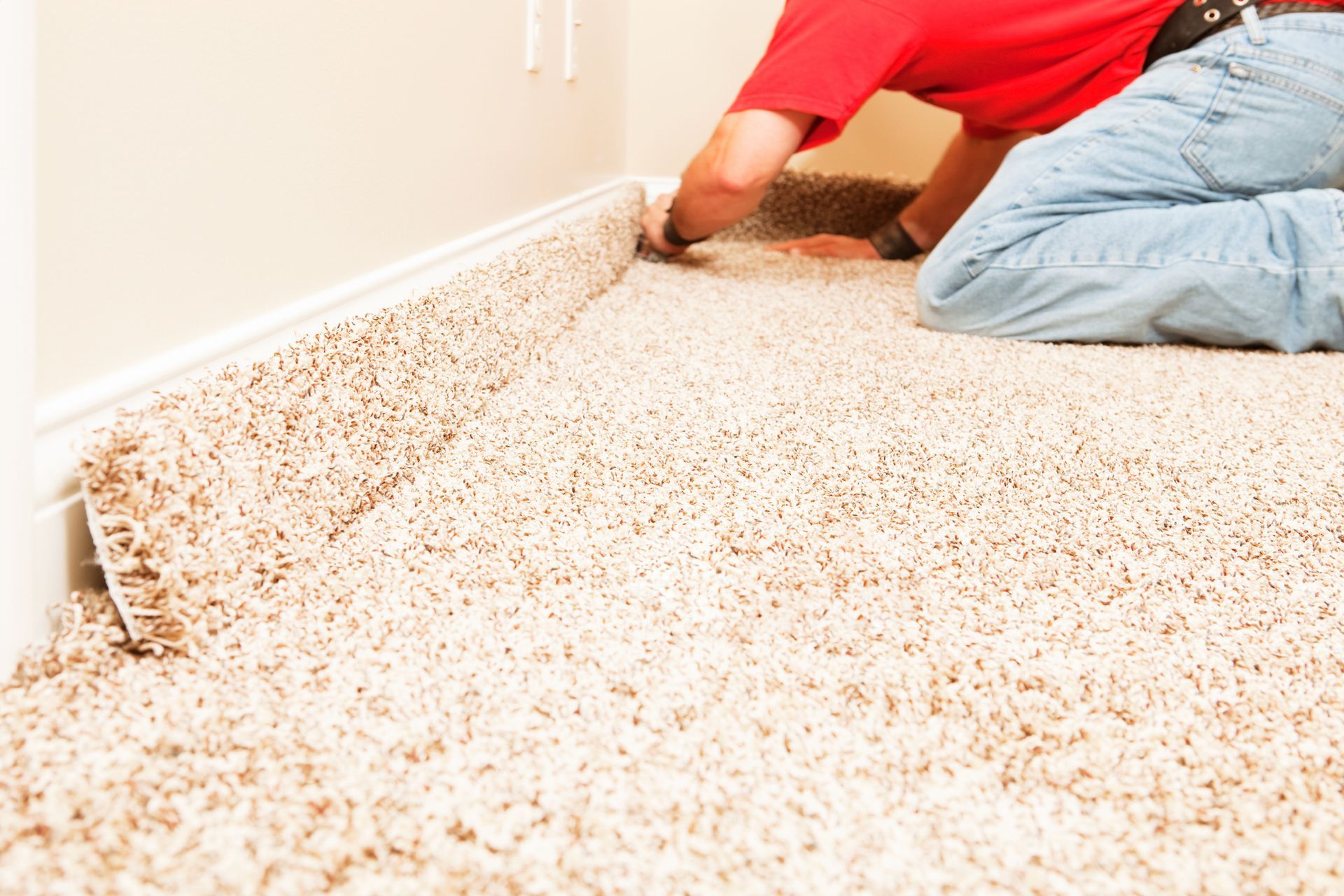 A man is laying carpet on the floor in a room.