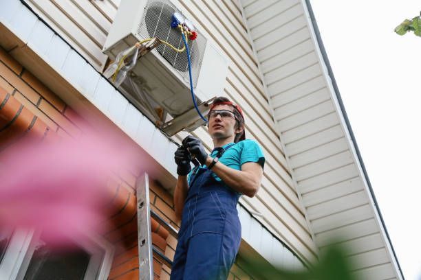 Technician checking AC unit with pressure gauge during home maintenance.