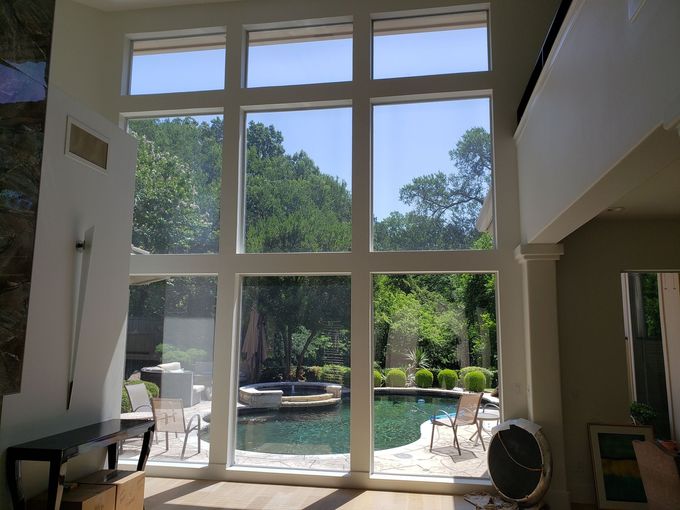 Bright living room with tall windows overlooking a sunny backyard patio and trees
