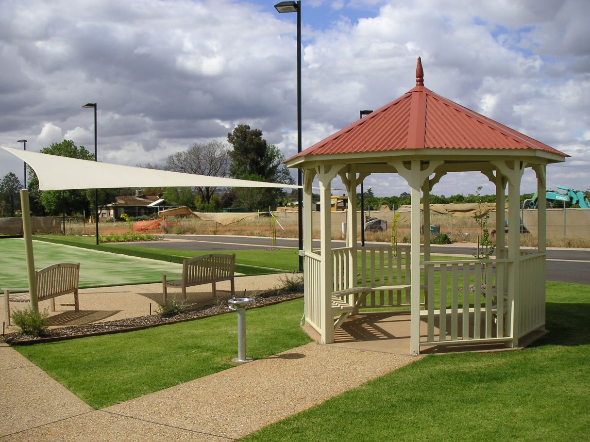 A Gazebo With A Red Roof Sits In The Middle Of A Lush Green Field - Gazebos in Albury, QLD