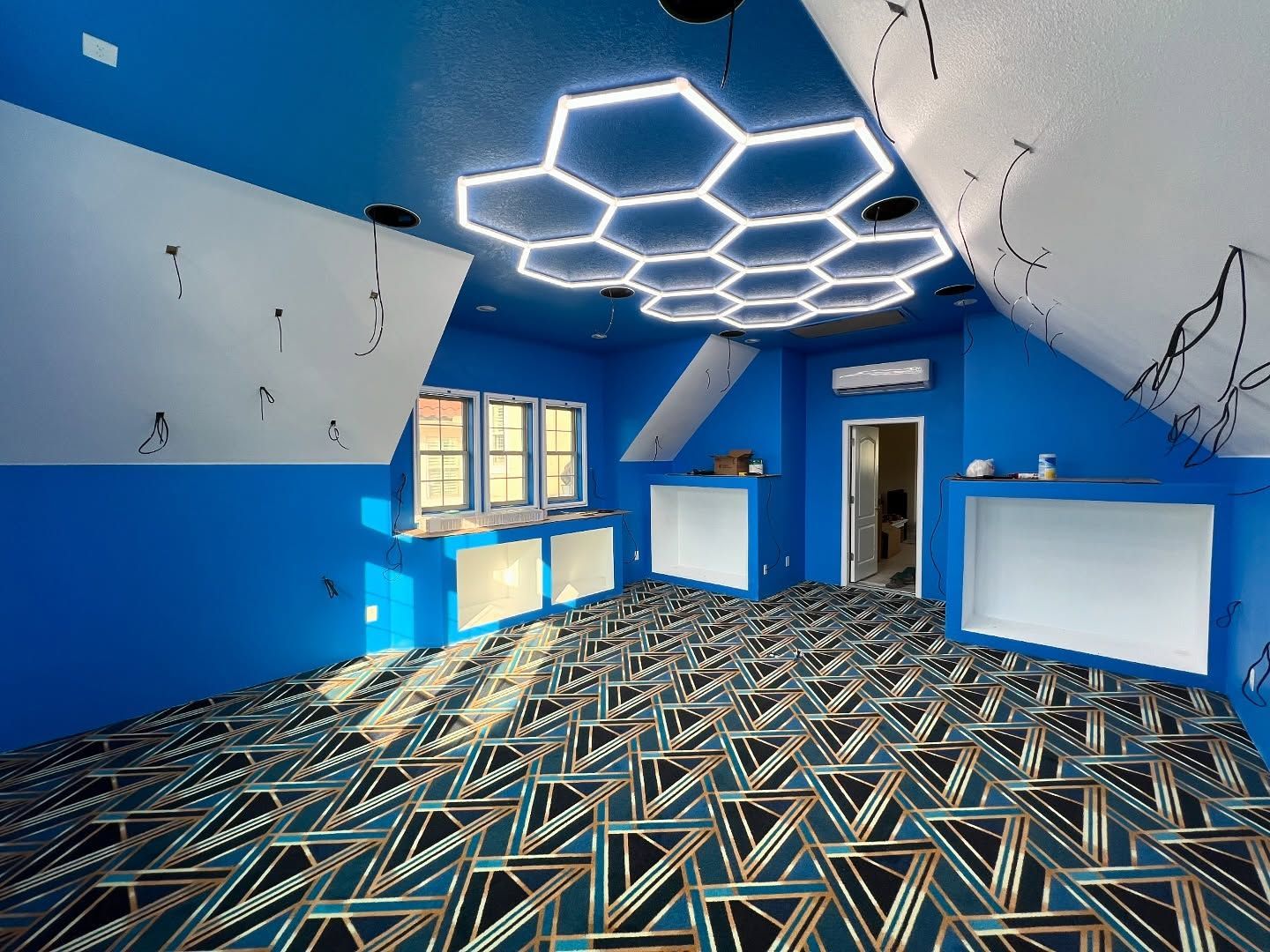 Blue room with honeycomb lights, geometric carpet, and slanted walls.