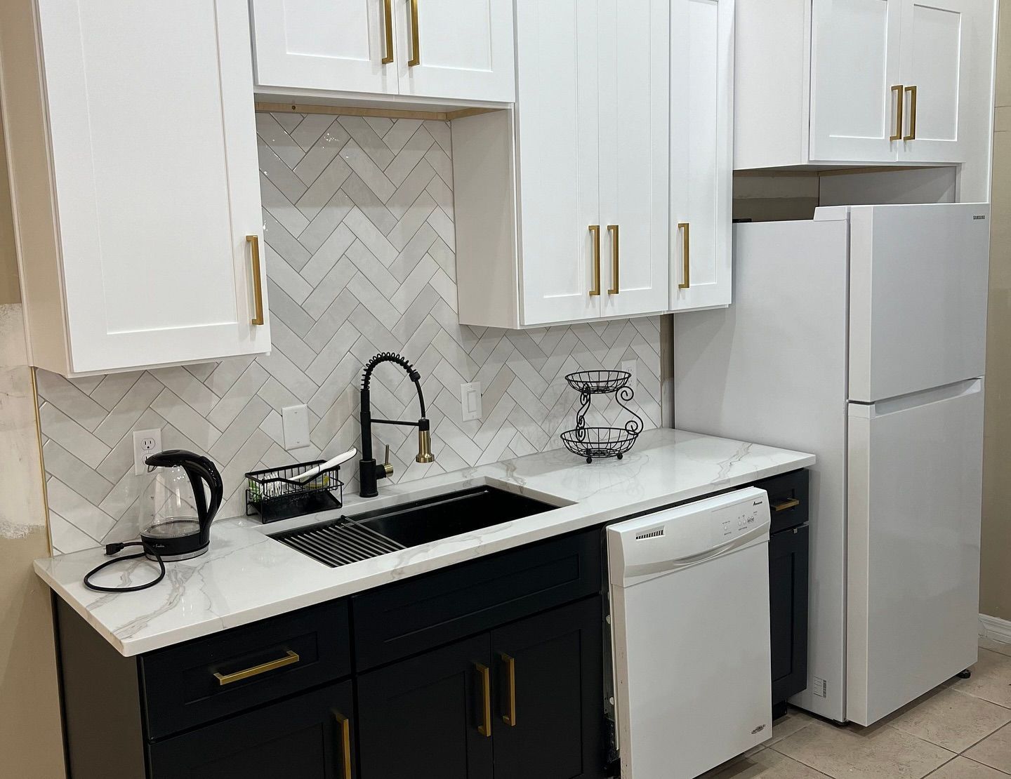 White and black kitchen with white cabinets, black countertops, and a white refrigerator.
