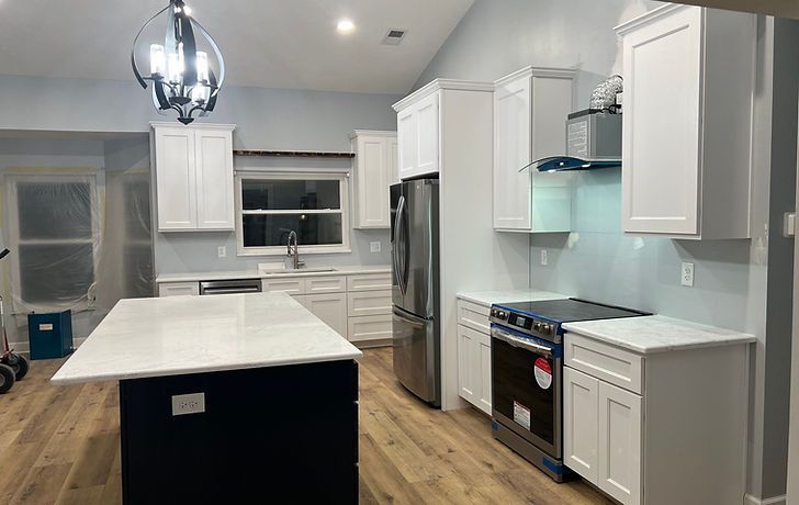 White kitchen with dark island and stainless steel appliances; light blue backsplash.