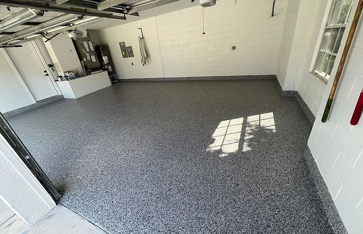 Garage with speckled gray epoxy flooring, white walls, and a window.