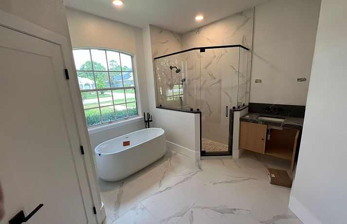 Bathroom with freestanding tub, marble-look tile, and glass shower.