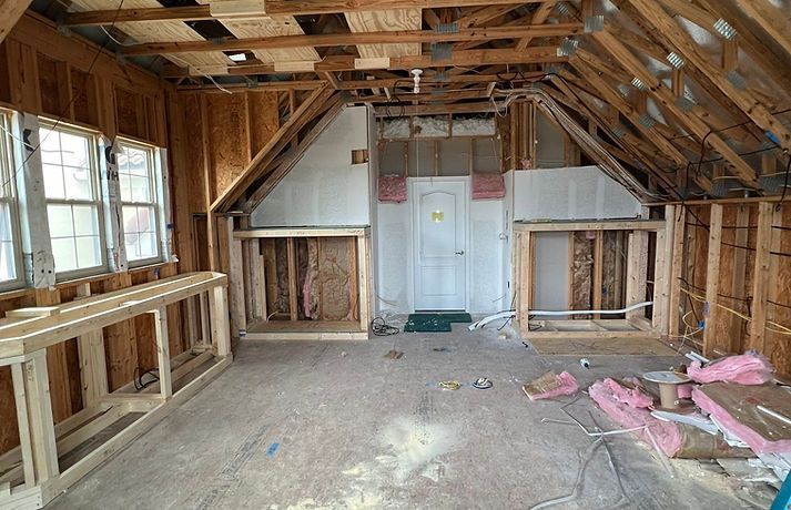 Interior of a room under construction, with exposed wooden framing and insulation.
