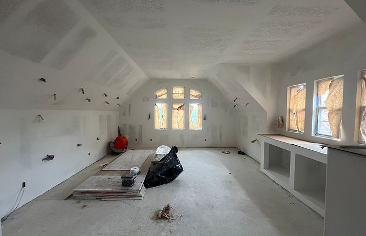 Interior of a room under construction with white walls, arched window, and unfinished built-in shelves.