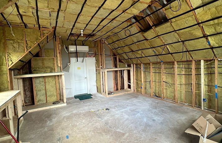 Interior of a room under construction with exposed wooden framing and insulation.