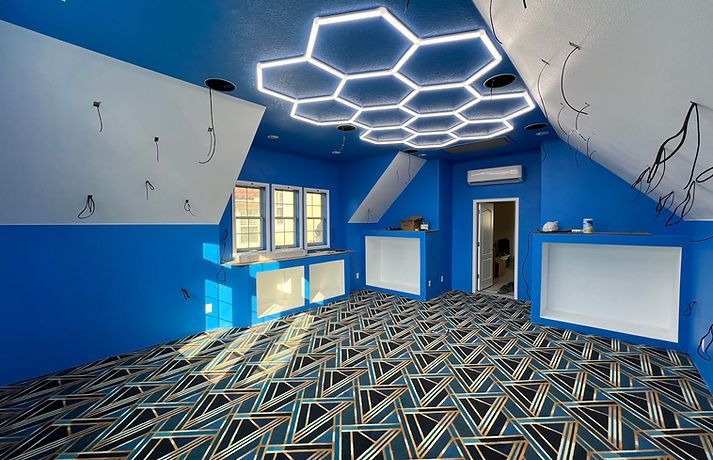 Blue room with honeycomb ceiling lights, geometric patterned floor, and white accents.