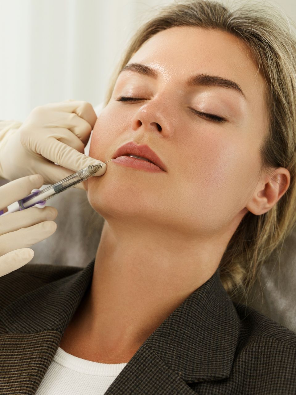 A woman is getting a botox injection in her lips