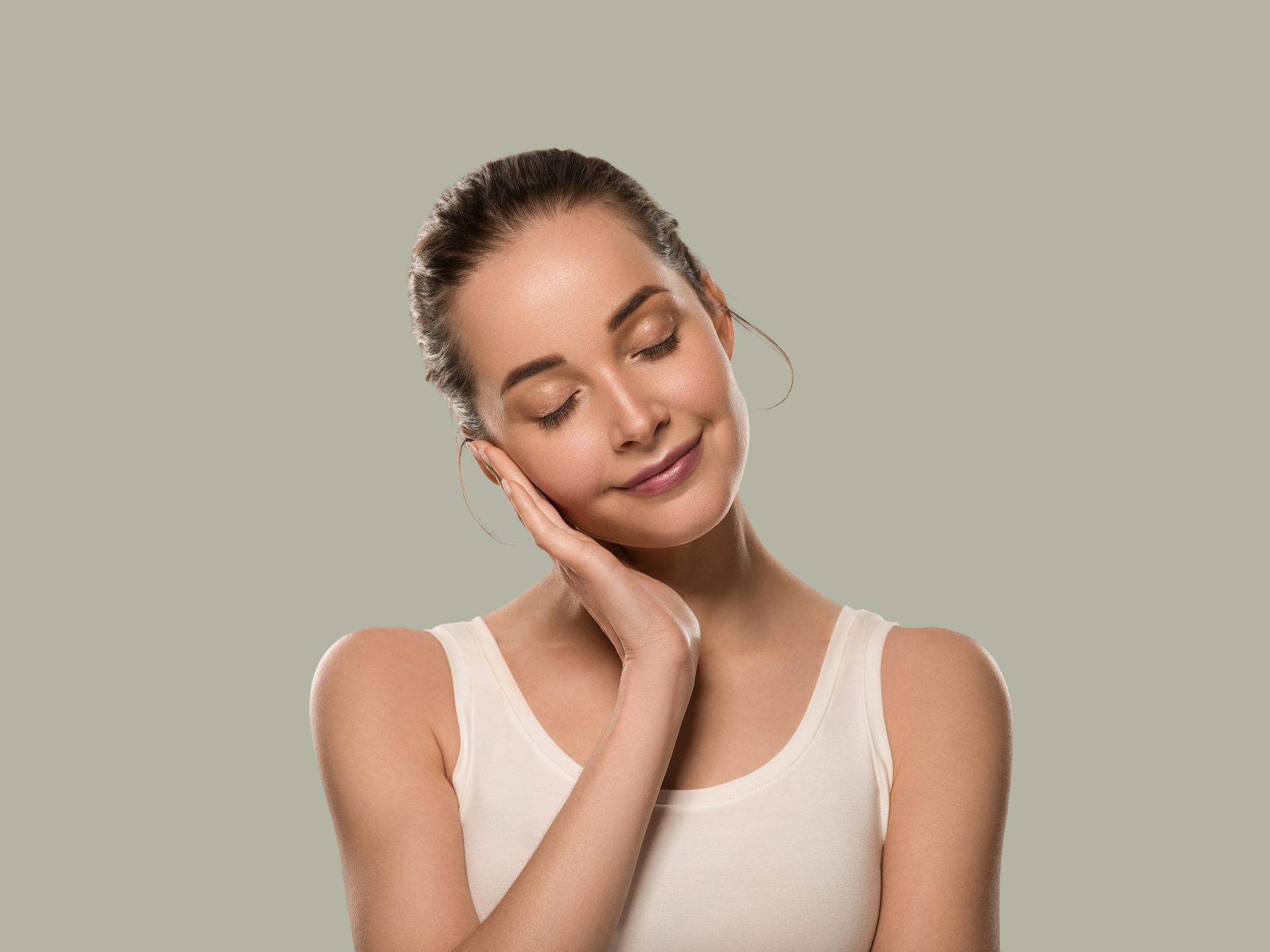 A woman is touching her face with her hands and smiling.